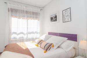 a white bedroom with a bed and a window at Apartamentos Turisticos Rent Guardamar in Guardamar del Segura