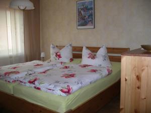ein Bett mit weißer Bettwäsche und roten Blumen darauf in der Unterkunft Ferienwohnung Herrig in Treis-Karden