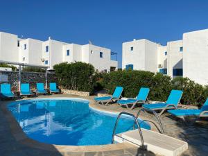 a swimming pool with blue lounge chairs and a hotel at Villa Les 4 Sœurs à Aspro Chorio - Paros in Aspro Chorio Paros