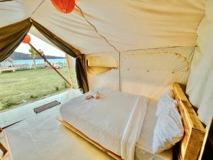 Diamond Glamping by BIO Management في تابانان: سرير في خيمة مطلة على المحيط