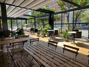 un patio con bancos de madera, mesas y ventanas en Auberge de Jeunesse HI Paris Yves Robert, en París