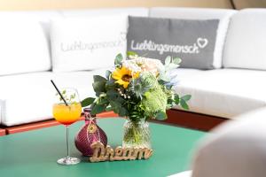 einen Tisch mit einer Vase Blumen und einem Glas Orangensaft in der Unterkunft Hotel-Residenz Immenhof in Maikammer