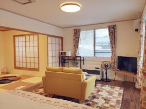 uma sala de estar com um sofá e uma televisão em Opopo home 竜宮店 em Otaru