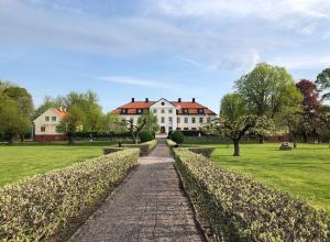 einen Weg vor einem großen weißen Haus in der Unterkunft Stjärnholmsslott in Nyköping