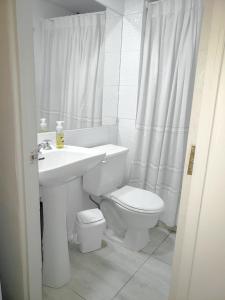 a white bathroom with a toilet and a sink at Casa Hostal Paso por La Serena in La Serena