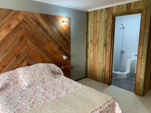 1 dormitorio con 1 cama y pared de madera en Viejoboldo_latrinchera en Los Rábanos