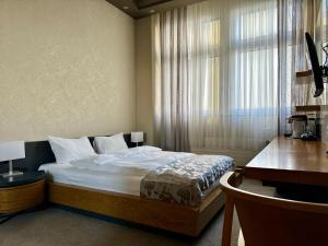 a bedroom with a bed and a desk and a window at Plaza Hotel Winterthur in Winterthur