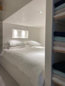 a bedroom with a white bed with a shelf with towels at HiP & STYLISCH B&B in Amsterdam