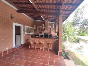 una cocina al aire libre con un bar con taburetes en un patio en Linda Casa de Campo Sitio Chácara em Campinas, en Campinas