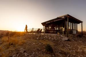 a man standing next to a building on a hill at Vingerklip Lodge in Vingerklip