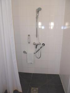 La salle de bains est pourvue d'une douche et d'un mur carrelé blanc. dans l'établissement ibis Paris Pont de Suresnes Longchamp, à Suresnes