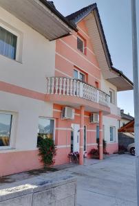 een roze en wit gebouw met een balkon bij Apartments Zupan in Šenčur