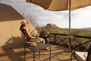 a woman sitting on a chair on a patio with a view at Vingerklip Lodge in Fingerklippe 
