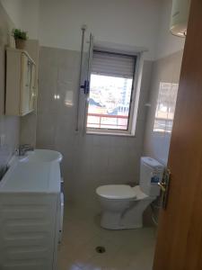 a bathroom with a toilet and a sink and a window at Apartament 1+1 Plazh Durrës in Durrës
