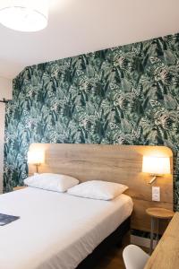 a bedroom with a bed with a green and white wallpaper at Logis Golfe Hotel in Vannes