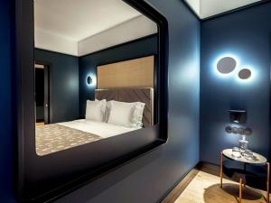 - un miroir dans une chambre avec un lit et une table dans l'établissement Axis Porto Club Aliados, à Porto