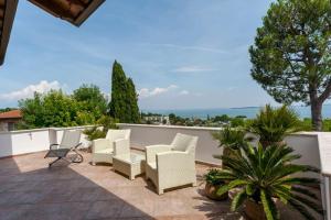un patio con sillas blancas y plantas en un balcón en VILLA ELENA, en Moniga del Garda