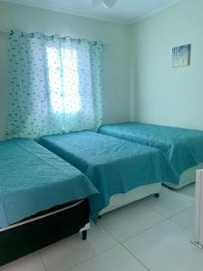 twee bedden in een slaapkamer met blauwe lakens en een raam bij Hotel Pousada universitária Bauru, CPO ,centrinho, funcraf ,USP, FACOP ,Agudos ,parque Vitória Régia , UNESP , maternidade Santa Izabel in Bauru