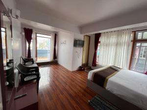 a hotel room with a bed and a desk and windows at Royal Vista - Guest House in Darjeeling