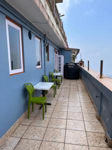 a patio with green chairs and tables on a blue building at Royal Vista - Guest House in Darjeeling