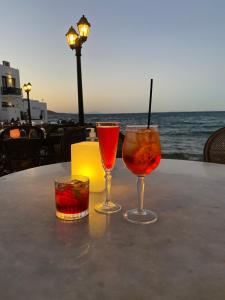 two glasses on a table with the ocean in the background at Villa Les 4 Sœurs à Aspro Chorio - Paros in Aspro Chorio Paros