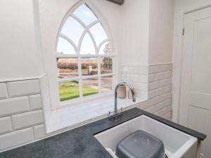 baño con lavabo y ventana en The Coach House, en Cornhill-on-tweed
