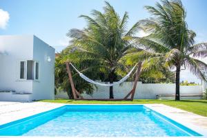 una piscina con una hamaca frente a una casa en Casa Incrível na Praia de Jacumã por Carpediem en Ceará-Mirim