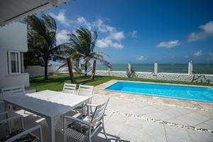 un patio con tavolo e sedie accanto alla piscina di Casa Incrível na Praia de Jacumã por Carpediem a Ceará-Mirim