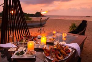 a table with plates of food and candles on the beach at Ceylon Serenity Villa in Beruwala