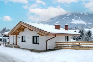 een huis bedekt met sneeuw met een berg op de achtergrond bij Appartement Hagenberger in Westendorf