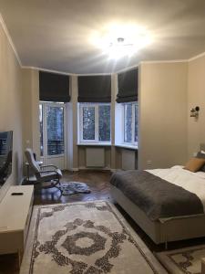 a bedroom with a bed and a chair and windows at апартаменти на вул Кобилянської з балконом in Chernivtsi