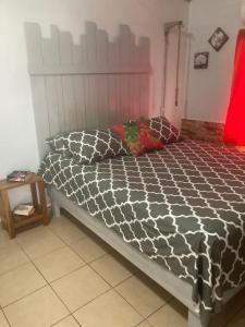 a bed with a black and white comforter in a bedroom at Caribbean Comfort in Puerto Viejo