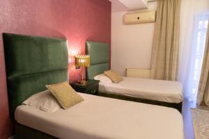 Habitación de hotel con 2 camas con detalles en verde en Phoenicia Suites Baneasa, en Bucarest