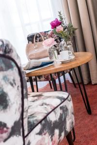 einen Tisch mit einer Vase aus Blumen und zwei Stühlen in der Unterkunft Die WUNDER s Ferienpension in Pörtschach am Wörthersee