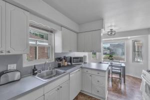 a kitchen with white cabinets and a sink and a table at 10 Minutes from Metro Airport! Parking on Premises in Allen Park