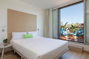 - une chambre avec un grand lit et une grande fenêtre dans l'établissement SmartRoom Barcelona, à Barcelone