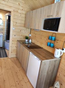 a kitchen in a log cabin with a sink and a microwave at Domki nad morzem Jula in Wrzosowo