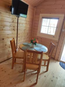 a dining room with a table and chairs and a television at Domki nad morzem Jula in Wrzosowo