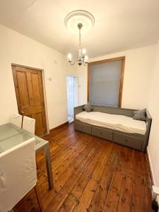 a bedroom with a bed and a wooden floor at Spacious flat with patio garden in Raynes Park