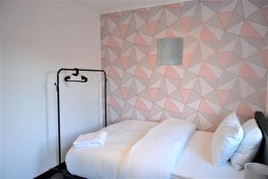 1 dormitorio con cama blanca y pared geométrica en London Zone 2, 2 Bedroom House, en Londres
