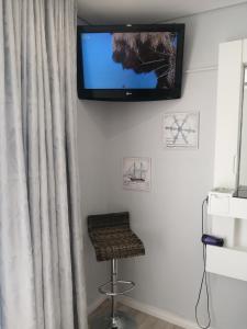 a tv hanging on a wall with a stool and a stool at Ocean room @ 66 Fynbos in Mossel Bay