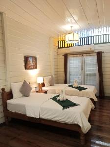 Duas camas num quarto com paredes brancas em Sangthong Heritage hotel โรงแรมแสงทองเฮอริเทจ em That Phanom