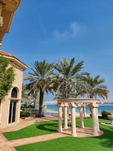 a house with a gazebo and palm trees at Palm's Largest Beachfront Estate in Dubai