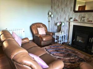 uma sala de estar com um sofá de couro e uma cadeira em Mackenzie 25 em Stornoway