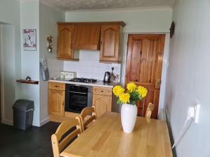 a kitchen with a table and a vase with yellow flowers at Mackenzie 25 in Stornoway