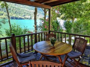 una mesa de madera y sillas en una terraza con vistas al agua en Villaggio Turistico Il Lago Dorato, en Carlazzo