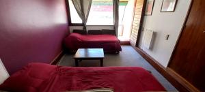 Departamento Penitentes Lomas Blancas في لوس بينيتنتس: غرفة معيشة مع أريكة حمراء وطاولة