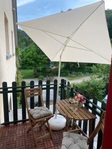 een tafel en stoelen met een witte parasol op een patio bij Camping Waldfrieden in Saarburg