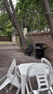 2 weiße Stühle, ein Tisch und ein Kamin in der Unterkunft COMPLEJO DRUMMOND en el Camino del Vino in Ciudad Lujan de Cuyo