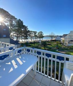 a white bench on a balcony with a view of the ocean at Grand Appartement duplex vue mer in Fouesnant